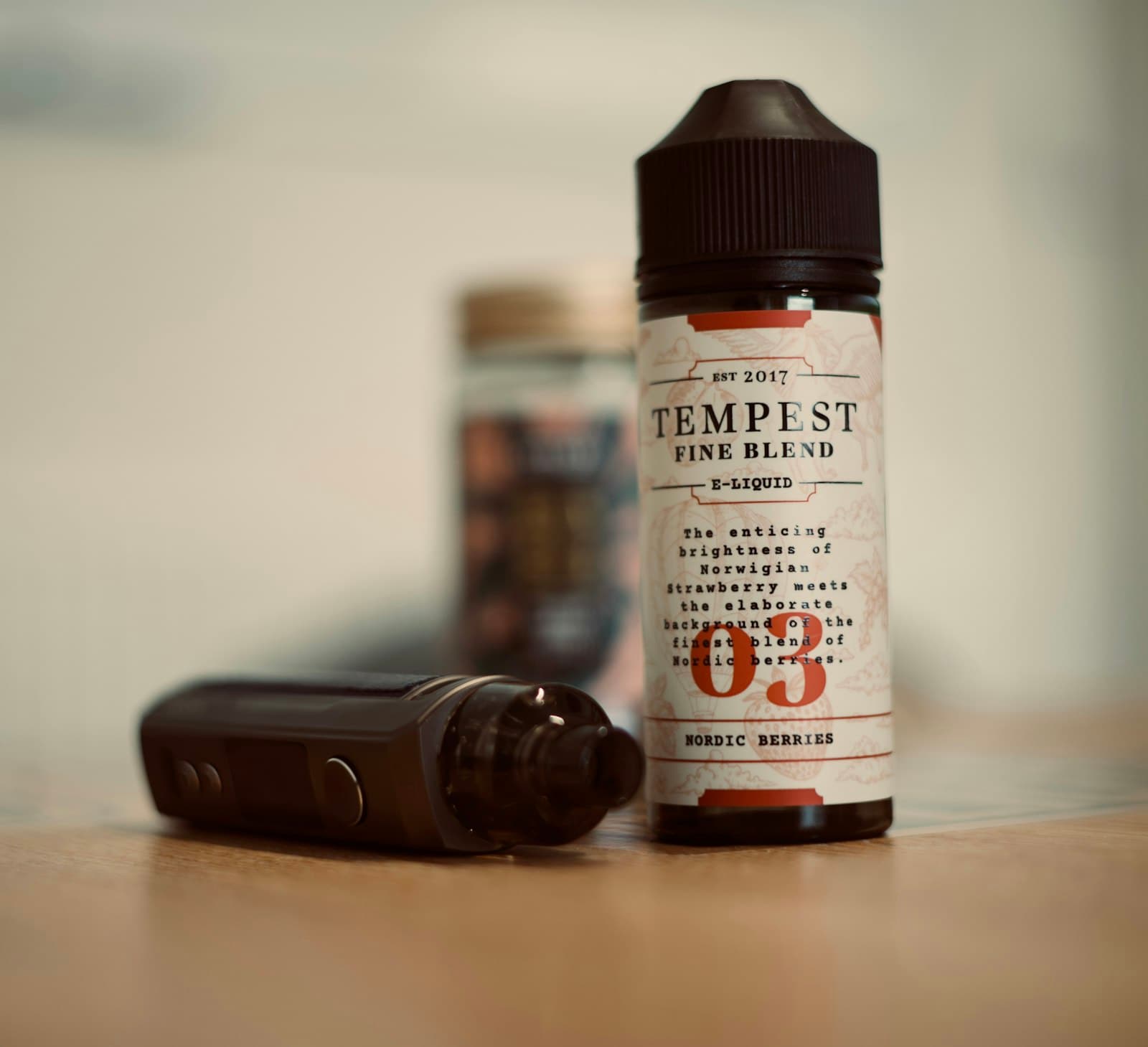A small e-liquid bottle standing next to a pod vaping device on a flat surface