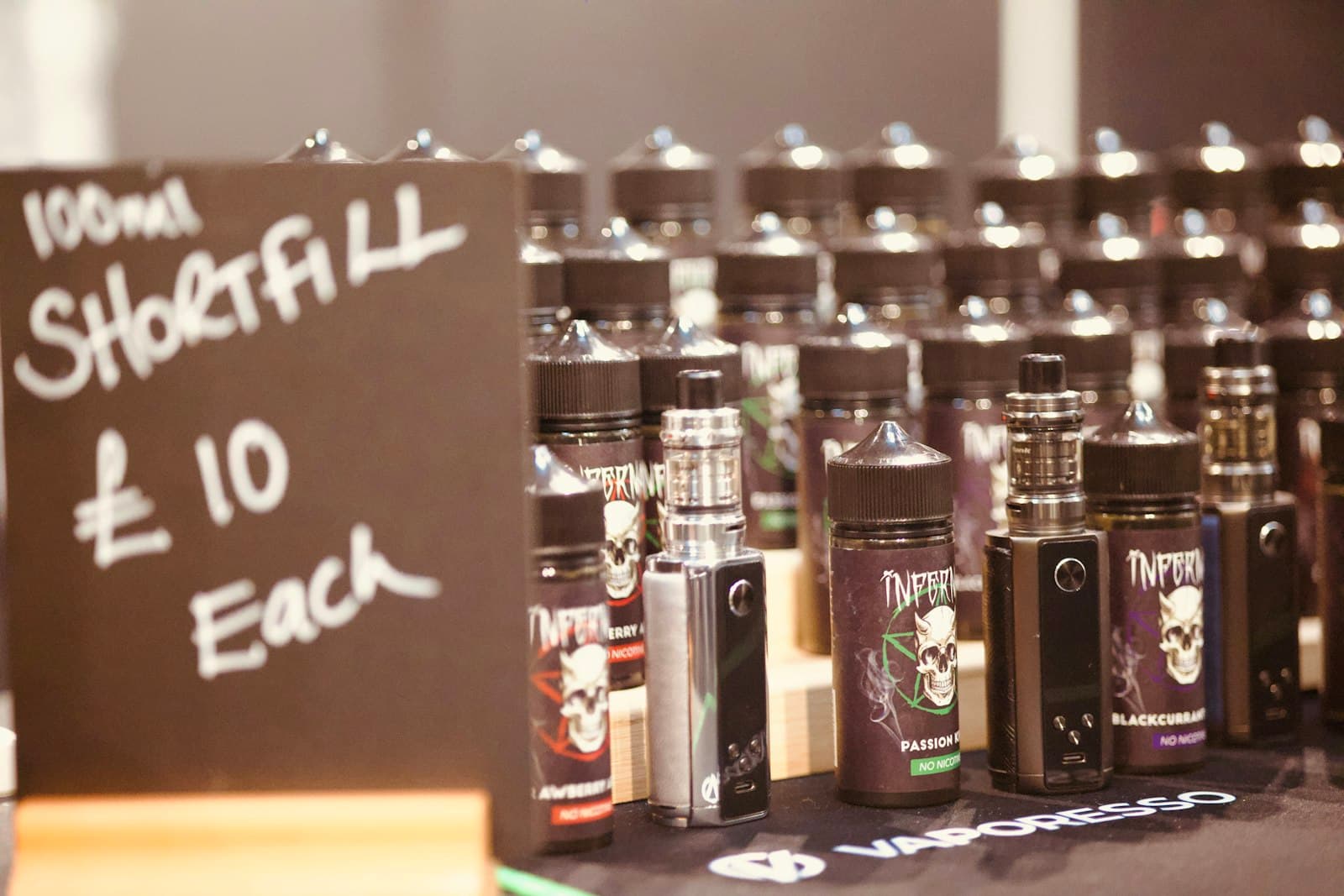 A shelf lined with a range of small e-liquid bottles of varying colours