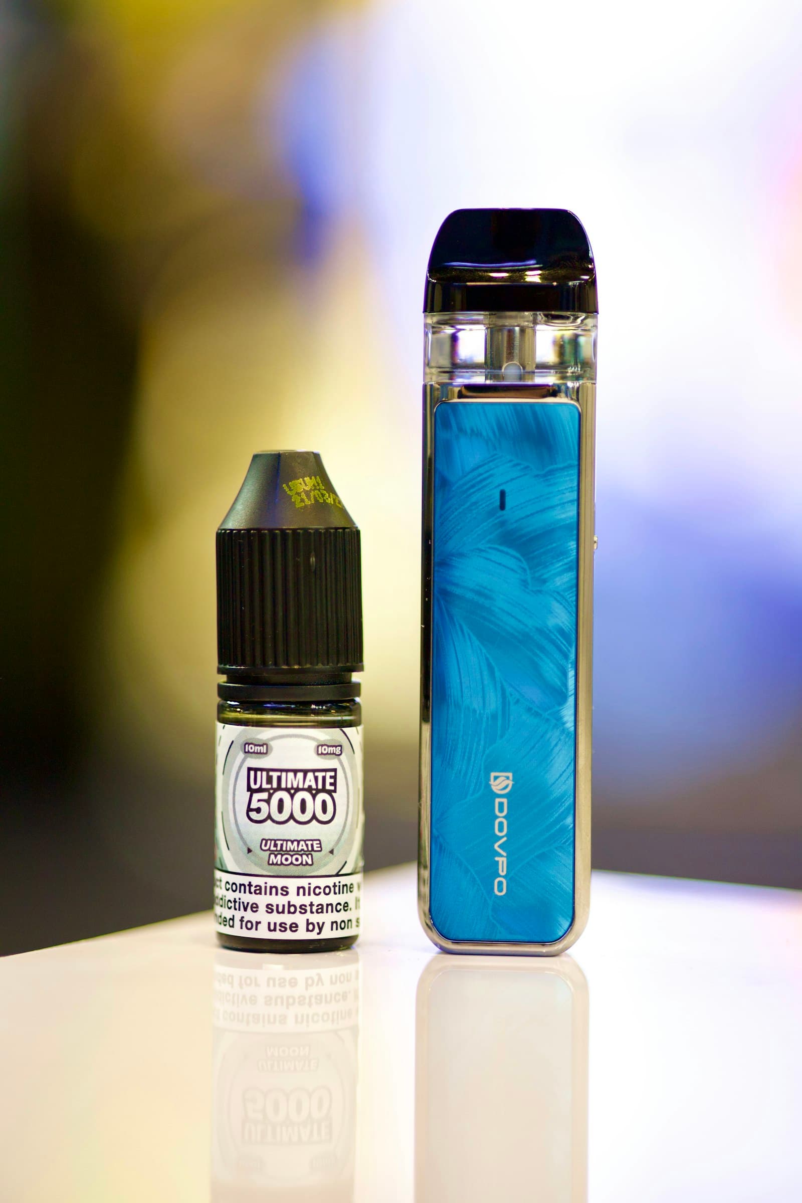 A compact pod vaping device standing next to a small e-liquid bottle