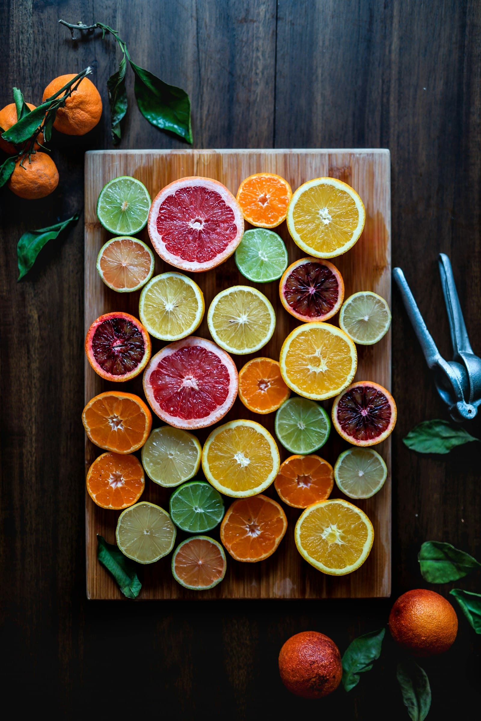 Assorted sliced citrus fruits including lemon, lime and orange arranged on a wooden chopping board